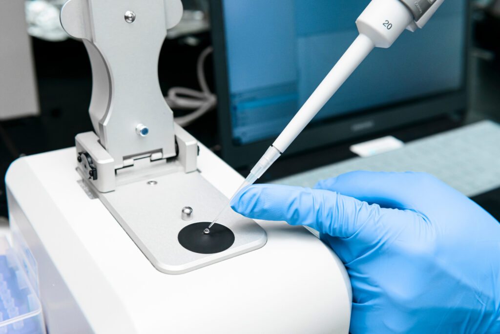 Scientist pipettes sample onto the low pedestal of Nanodrop for measuring the concentration of nucleic acid and purified proteins