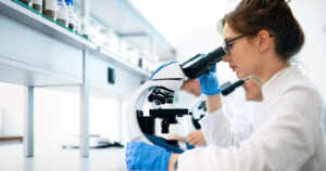Pathologist views sample through microscope.